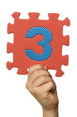 Image showing Children hand holding the number Three. White isolated number