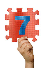 Image showing Children hand holding the number Seven. White isolated number