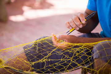 Image showing Fisherman repairing fishing net