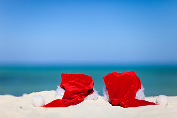 Image showing Two red Santa hats on beach