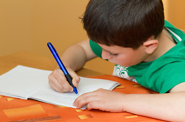 Image showing boy writting homework from school in workbook