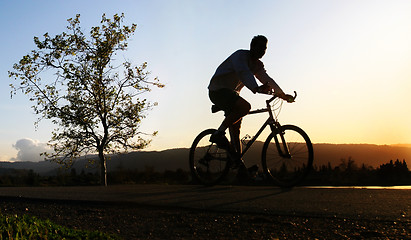 Image showing Man riding his bike at sunset