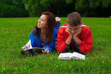 Image showing two teenagers studying outdoors on grass