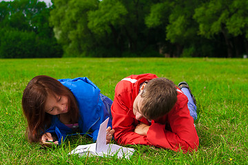 Image showing two teenagers studying outdoors on grass