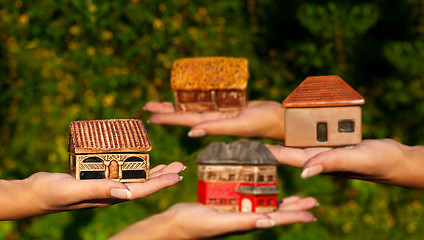 Image showing Four different houses in human hands