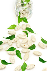 Image showing Herbal supplement pills and fresh leaves  spilling out of bottle