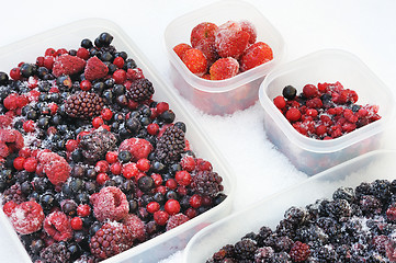 Image showing Plastic containers of frozen mixed berries in snow