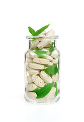 Image showing Herbal supplement pills and fresh leaves  in glass – alternative medicine concept