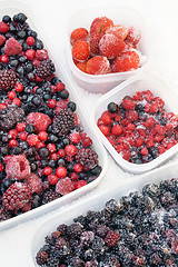 Image showing Plastic containers of frozen mixed berries in snow 