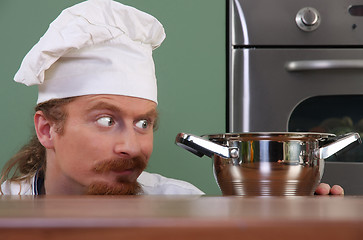 Image showing Funny young chef strange looking at pot