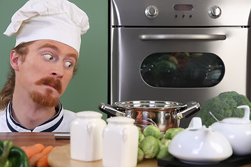 Image showing Funny young chef strange looking at pot