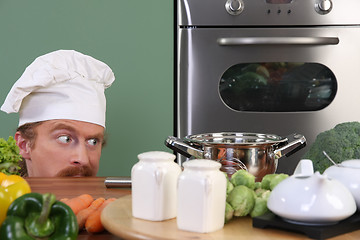 Image showing Funny young chef strange looking at pot