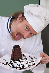 Image showing Funny young chef eating a piece of cake