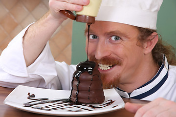 Image showing Funny young chef added chocolate sauce at piece of cake