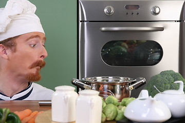 Image showing Funny young chef strange looking at pot