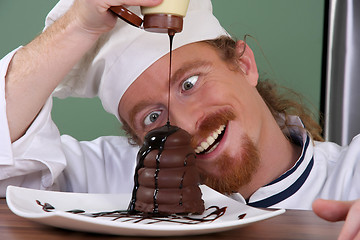 Image showing Funny young chef added chocolate sauce at piece of cake