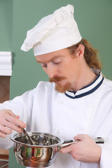 Image showing young Chef tasting food with a tablespoon 