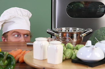 Image showing Funny young chef strange looking at pot