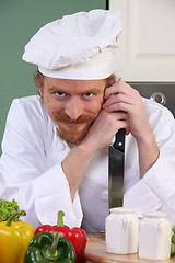 Image showing Funny young chef with a knife in kitchen 