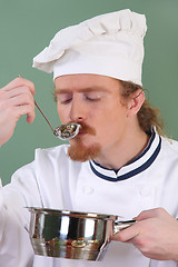 Image showing young Chef tasting food with a tablespoon