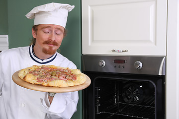 Image showing Young chef smelling italian pizza in kitchen
