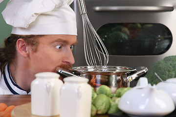 Image showing Funny young chef strange looking at pot