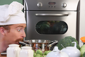 Image showing Funny young chef strange looking at pot