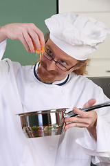 Image showing Funny young chef add carrots in the pot