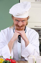 Image showing Funny young chef with a knife in kitchen