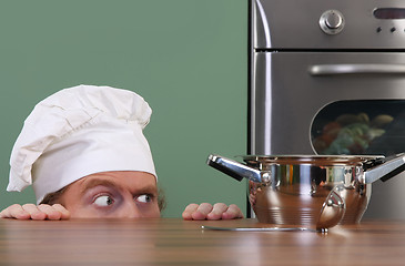 Image showing Funny young chef strange looking at pot