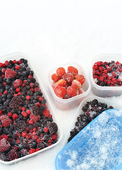 Image showing Plastic containers of frozen mixed berries in snow 