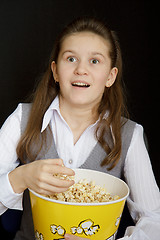 Image showing surprised girl with popcorn on a black background