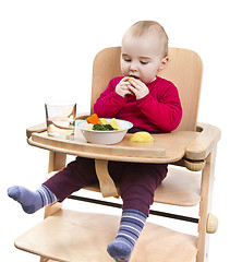 Image showing young child eating in high chair