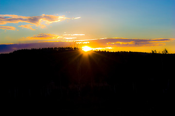 Image showing sunset over the forest in the clouds