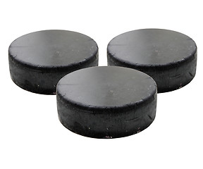 Image showing Three old black hockey puck.