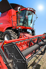 Image showing combine harvester on a wheat field with a blue sky