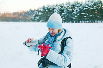 Image showing The woman pours from a thermos tea, in winter on walk