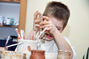 Image showing child  boy shaping clay in pottery studio