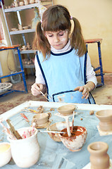 Image showing child girl shaping clay in pottery studio