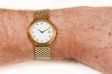 Image showing Gold watch with white face on hairy wrist