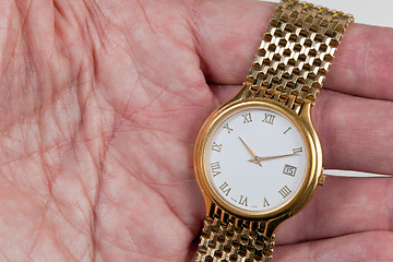 Image showing Gold watch with white face in palm of hand