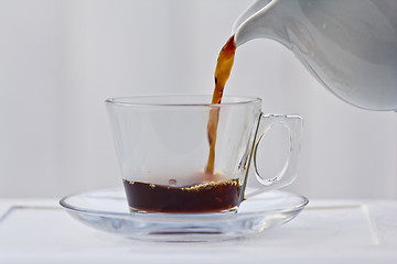 Image showing Pouring coffee into a quarter full cup
