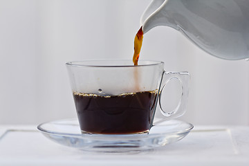 Image showing Pouring coffee into a half full cup