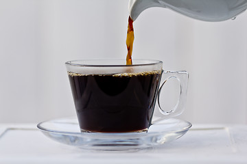 Image showing Pouring coffee into an almost full cup