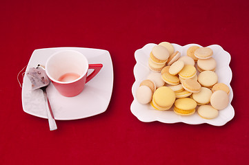 Image showing Empty Cup of tea and plate of mixed macaroons on a velvet tablec