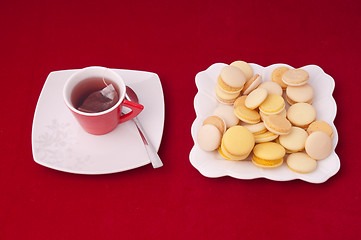 Image showing Cup of tea and plate of mixed macaroons on a velvet tablecloth