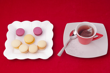 Image showing Cup of tea and smile of macaroons on velvet tablecloth