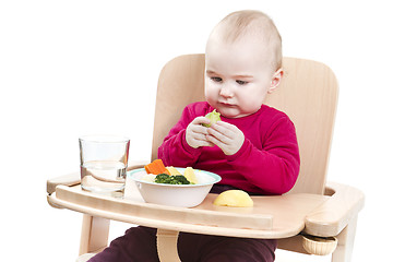 Image showing young child eating in high chair