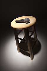 Image showing Microphone Laying on Wooden Stool Under Spotlight