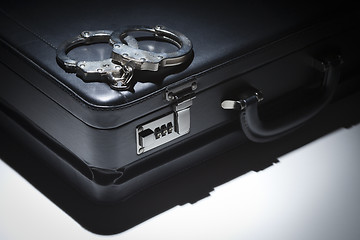 Image showing Pair of Handcuffs and Briefcase Under Spot Light